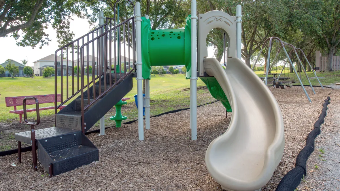 A colorful and inviting playground featuring swings, slides, benches, and a picnic table – where laughter and joy abound.