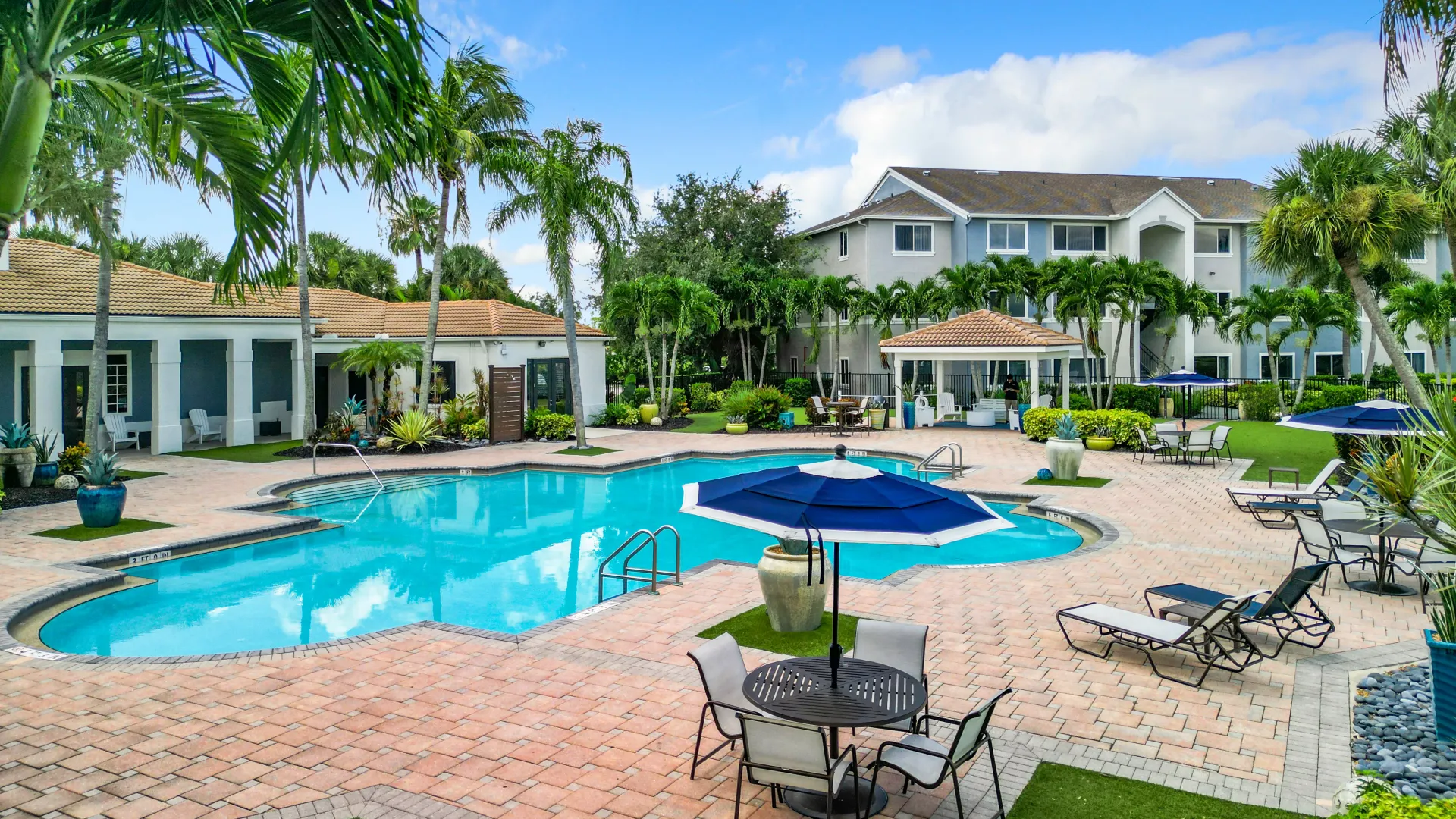 Pristine pool area with lounge chairs, shaded seating areas, and lush tropical landscaping, offering a relaxing and community-focused environment.