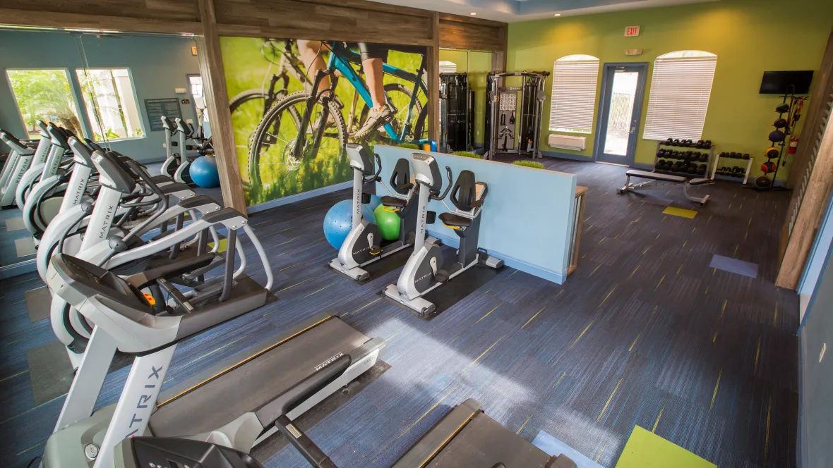 A well-lit resident gym with cardio equipment and weight machines, ready to energize your workouts.