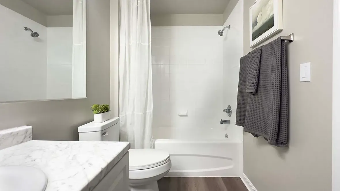 Luxurious guest bathroom space with ample mirrors, an expansive vanity, and wood-like flooring.