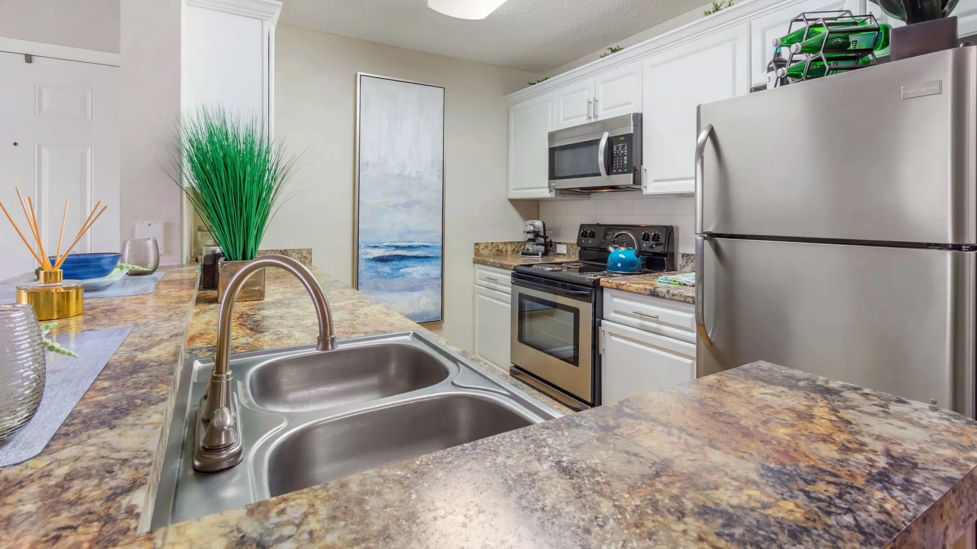 Modern kitchen at Lexington Palms with golden mascarella countertops and stainless steel appliances.