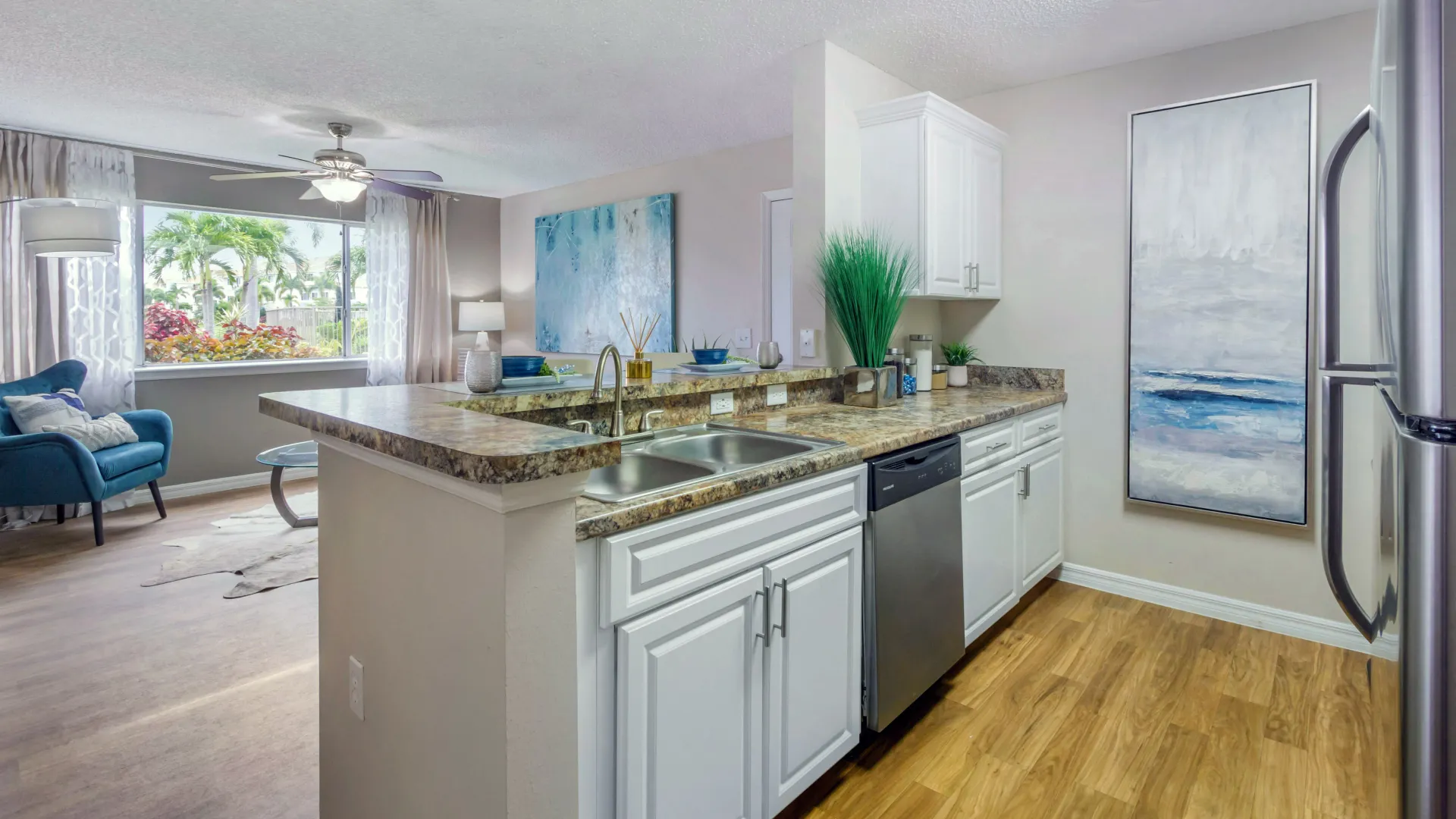 Kitchen interior at Lexington Palms with golden Mascarella countertops, white cabinets, and stainless steel appliances in an open-concept layout.