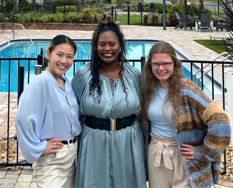 Ridgemar Commons leasing team posing in front of the community's resort-style swimming pool.