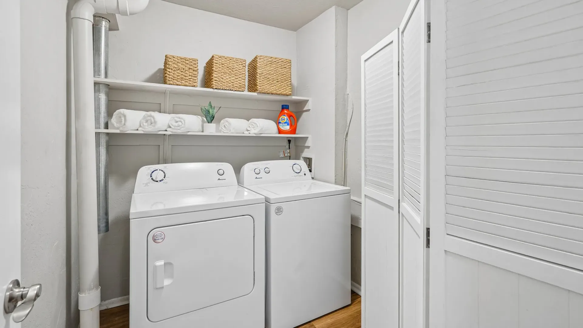 In-unit laundry room at Ridgemar Commons featuring a full-size washer and dryer, built-in storage shelves, and dedicated space for laundry essentials.