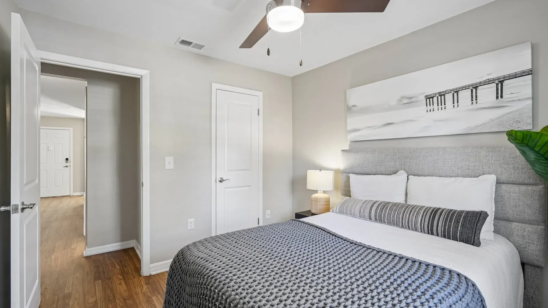 Bedroom featuring wood-style flooring, a ceiling fan, contemporary furnishings, neutral finishes, and a bright, functional layout.
