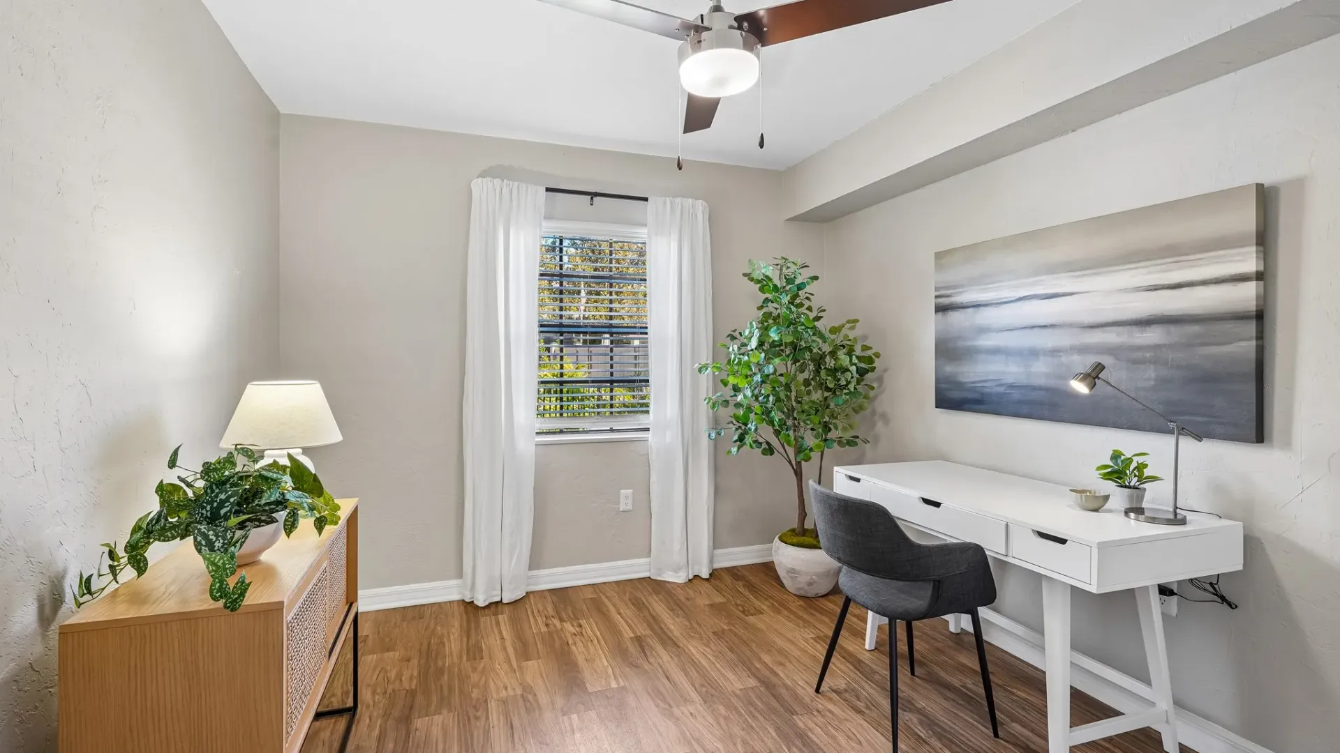 Bedroom or home office featuring wood-style flooring, a window with natural light, a ceiling fan, and a dedicated workspace with a desk and chair.