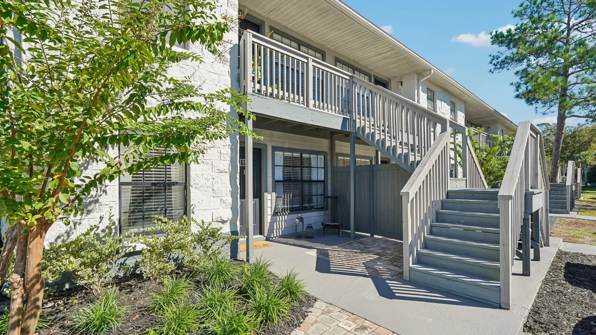 Private ground-floor patio at Ridgemar Commons featuring a covered outdoor space, privacy fencing, exterior apartment entrance, and landscaped surroundings.
