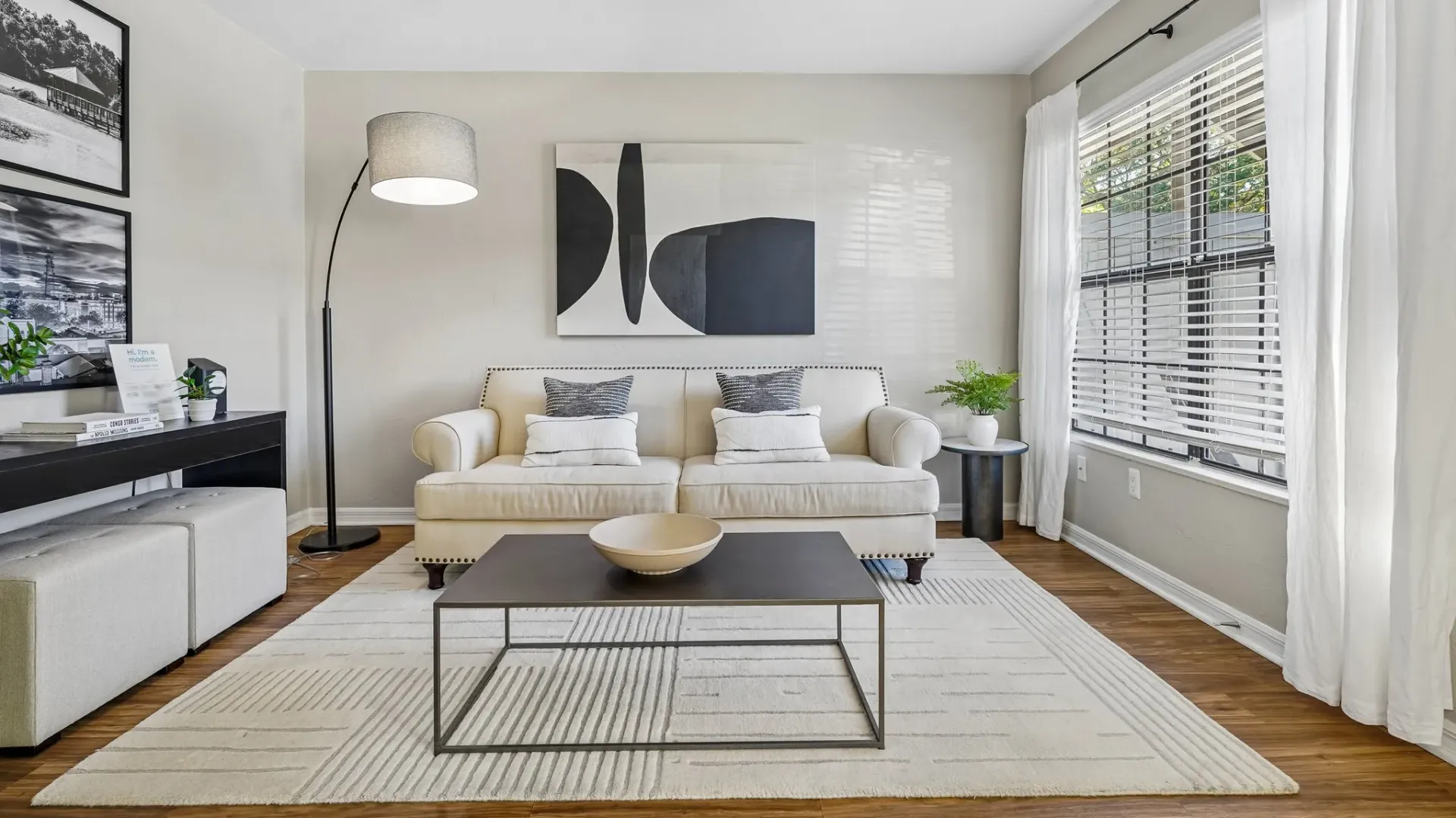 Living room at Ridgemar Commons featuring wood-style flooring, a large window with natural light, contemporary furnishings, and a spacious open layout.