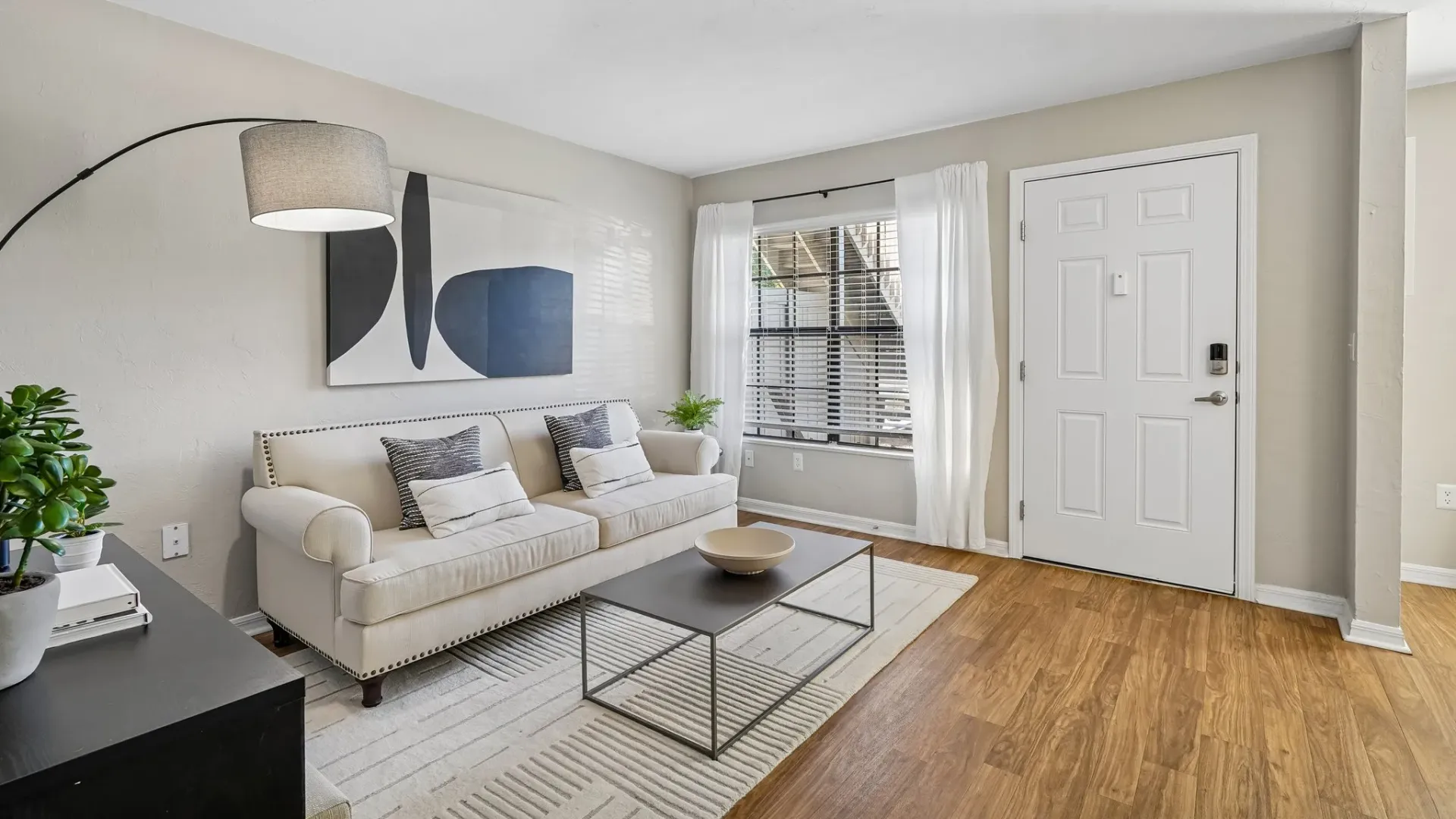 Living room at Ridgemar Commons featuring modern furnishings, wood-style flooring, natural light, a large picture window, and a comfortable open layout.