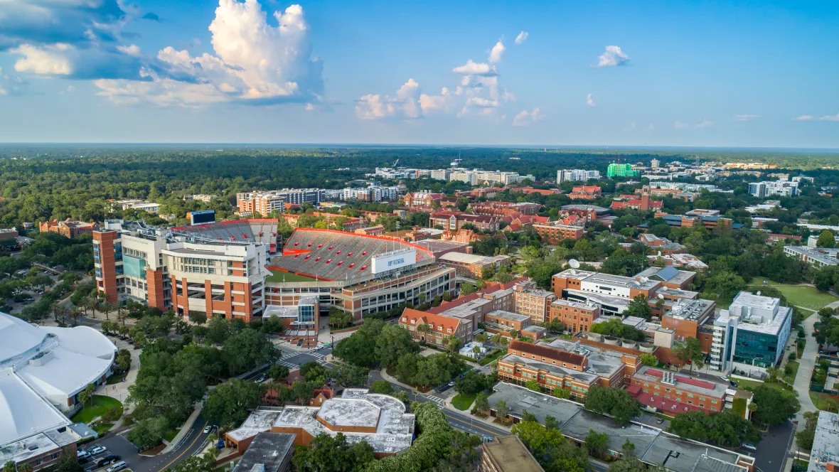 A panoramic aerial view of the sprawling UF campus, featuring the Ben Hill Griffin Stadium at Florida Field home to University of Florida football, as well as stretches of the landscape surrounding the City of Gainesville. 