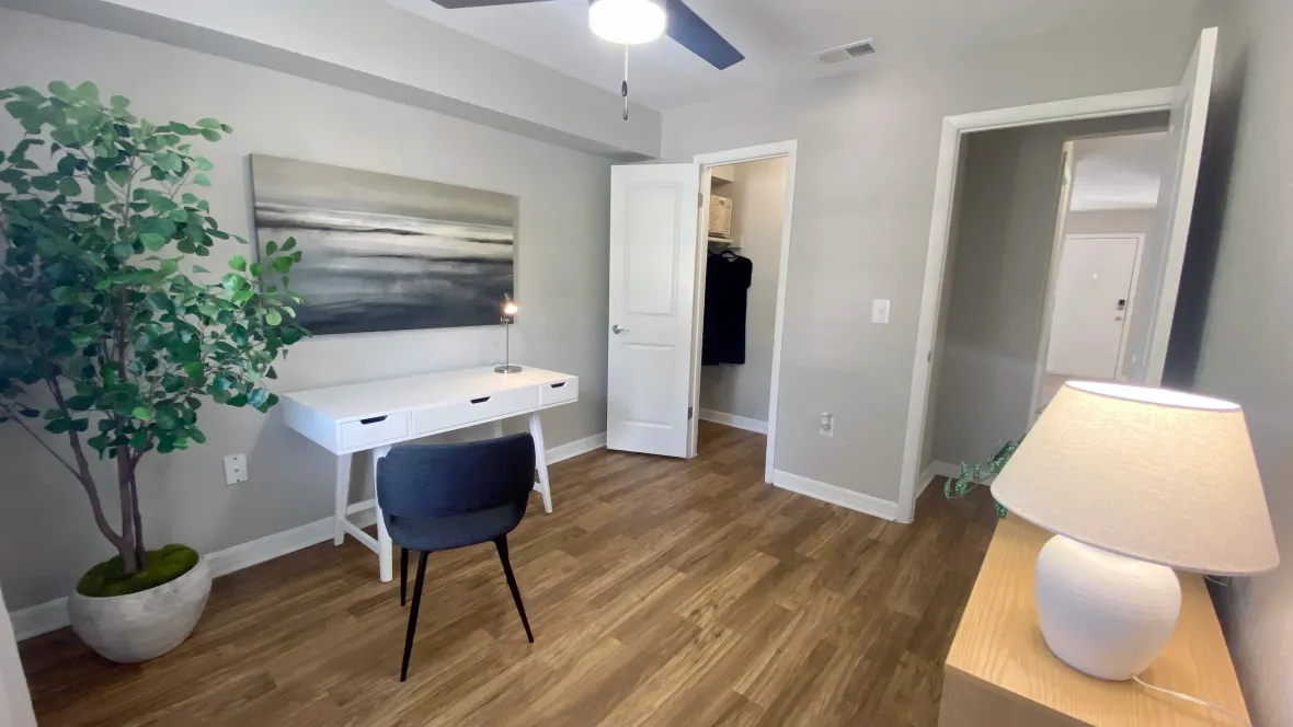 A second bedroom transformed into a stylish office space, featuring a bright ceiling fan with LED lights and a large walk-in closet for optimal storage.