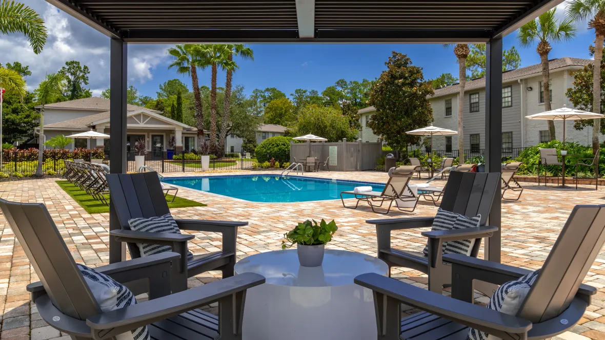 Shaded seating beneath the poolside pergola, providing a perfect spot for residents to enjoy conversations while avoiding direct sunlight.