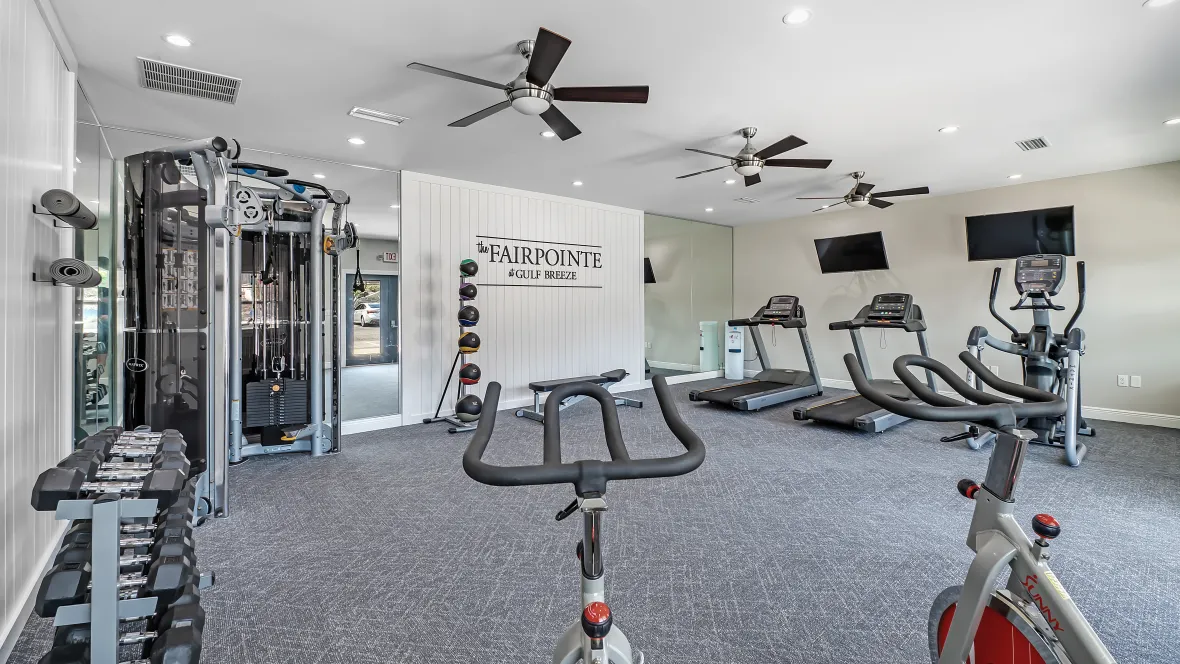 A well-appointed fitness center filled with modern workout gear and breezy fans, offering an invigorating yet serene atmosphere for a solid workout.