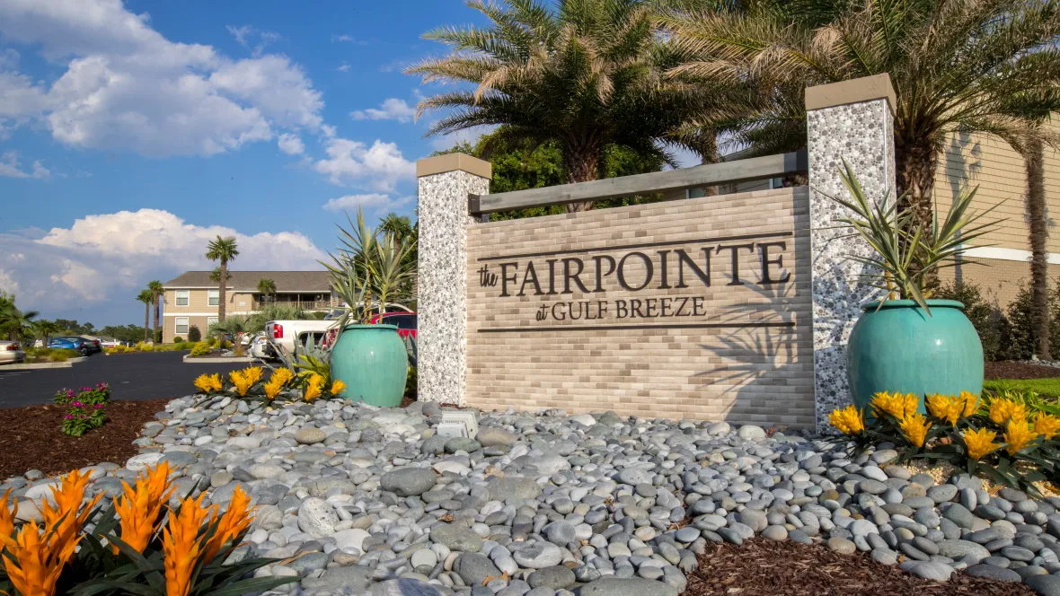 A bold stone-framed monument sign at the community’s entrance, symbolizing an invitation to luxurious coastal living.