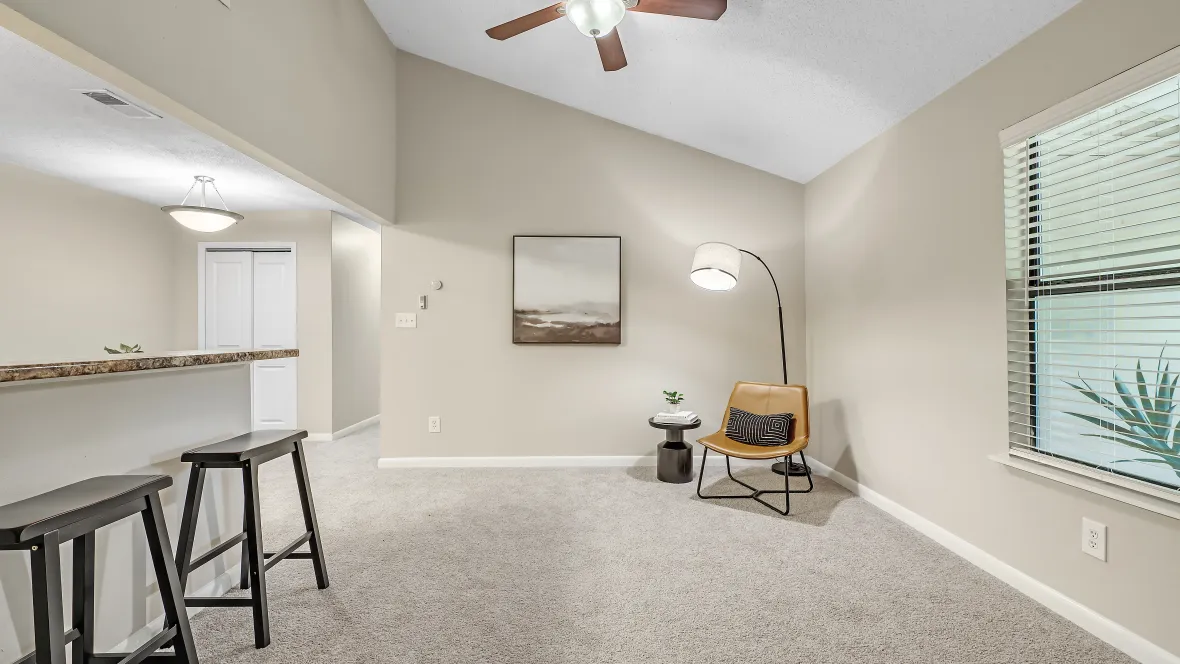 A living area featuring warm, inviting carpeting, pitched ceilings, and a multi-speed ceiling fan with lights, offering a spacious sanctuary for ultimate coziness.