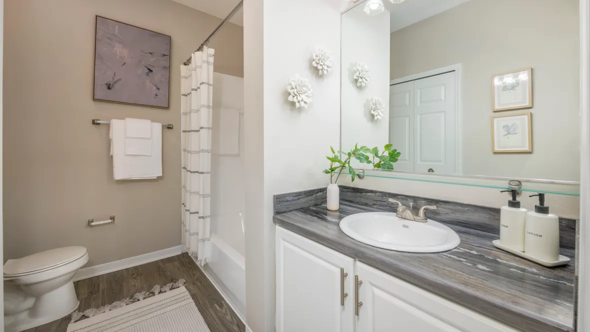 A lavishly appointed master bathroom, the epitome of refinement with wood-style flooring and a large vanity.