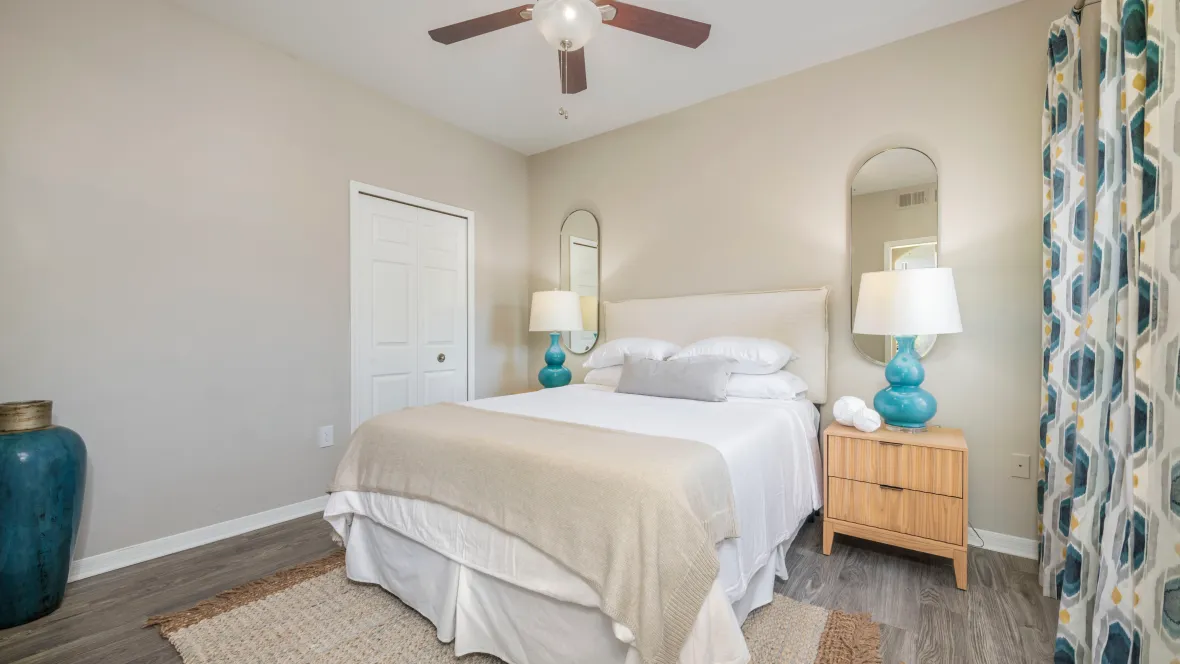 A generously sized guest bedroom with wood-style flooring, a generous closet, and an adjustable multi-speed ceiling fan.