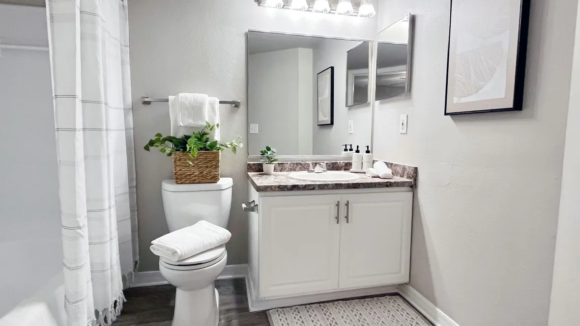 A stylish restroom with generous countertop space, large mirrors, and modern wood-like flooring.