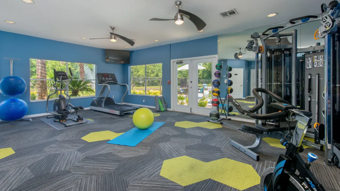 A vibrant, modern fitness center with green accents offers cardio and weight training equipment, including treadmills and a full-body workout machine.