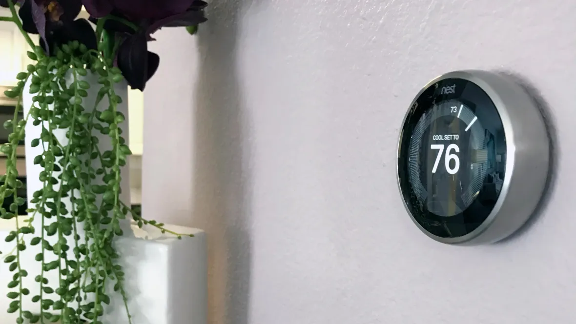 A sleek Nest thermostat display mounted on an apartment wall.