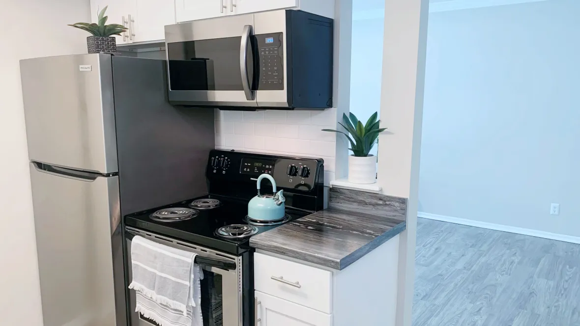 A studio apartment kitchen with sleek, full-size appliances, offering a harmonious blend of function and style in a cozy setting.