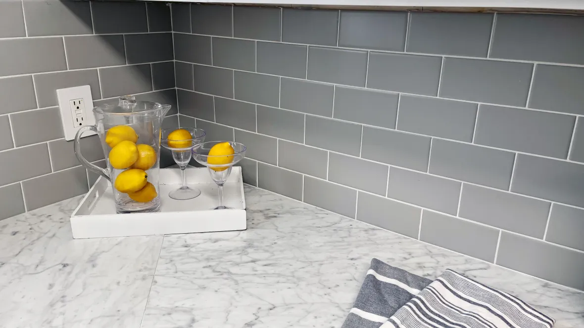 Close-up view of a sleek grey subway-style backsplash offering a bold and sophisticated charm to the heart of the home. 