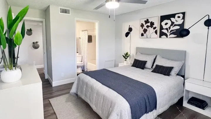 A master bedroom with queen size bed and plank flooring. 
