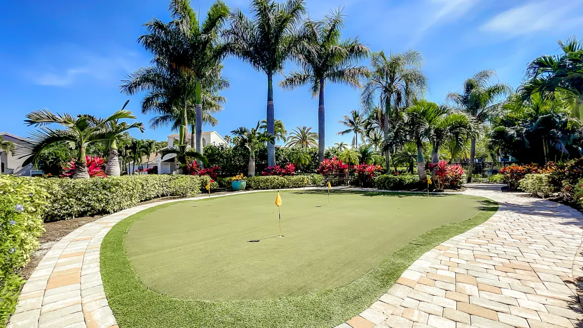 A beautifully landscaped putting green with surrounding pathways, inviting residents for leisurely putting practice amid tropical scenery.