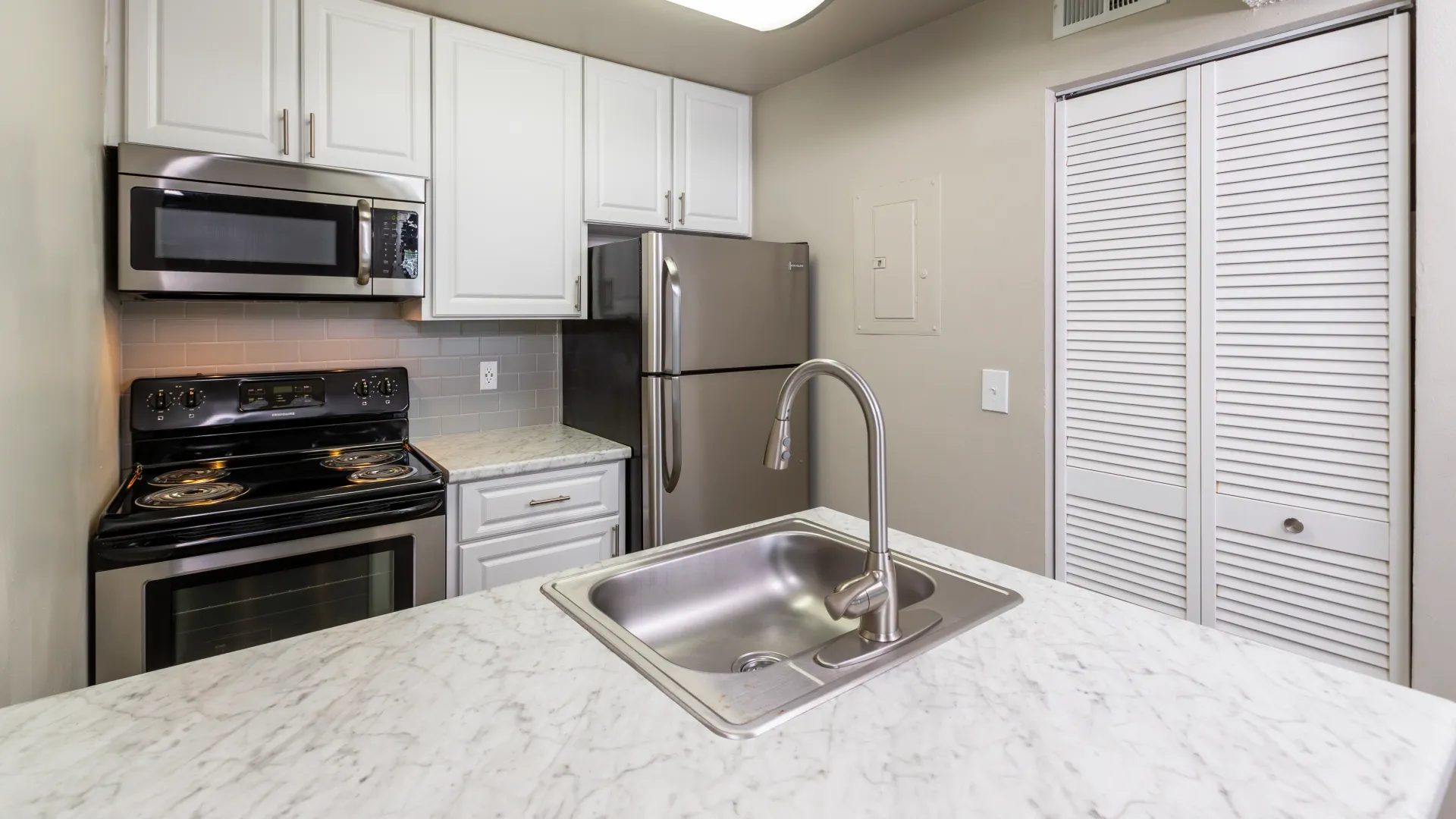 A revamped kitchen showcasing a luxurious stainless-steel appliance package, ample storage, and a gleaming white-marbled counterspace.