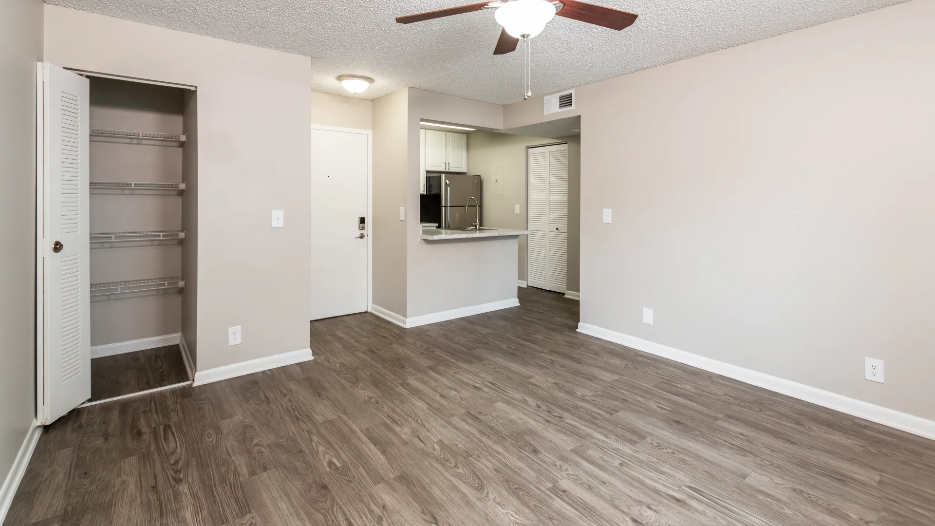 An open-concept living room with beautiful wood-planked floors effortlessly transitions into the kitchen with a look across the breakfast bar into the renovated culinary space. 