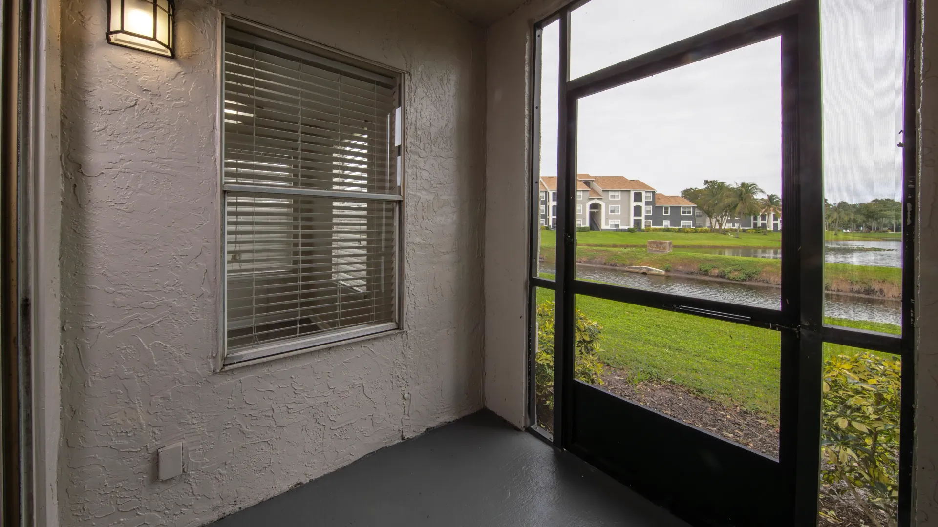 A private screened ground floor patio with unobstructed views of the community’s lake, green lawns, and pristine buildings.  