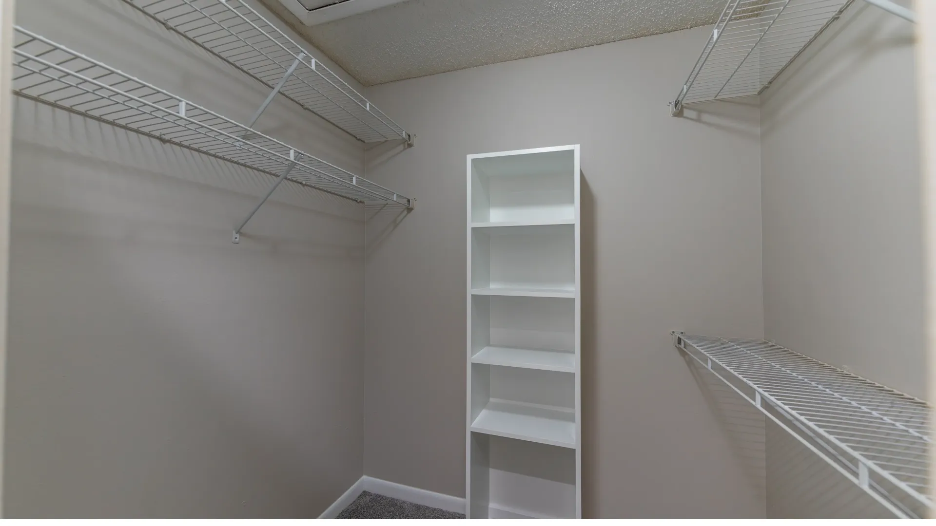 A infinite walk-in closet featuring customized open wire shelving and a bonus built-in bookcase, offering versatile storage for your wardrobe, shoes, and accessories.