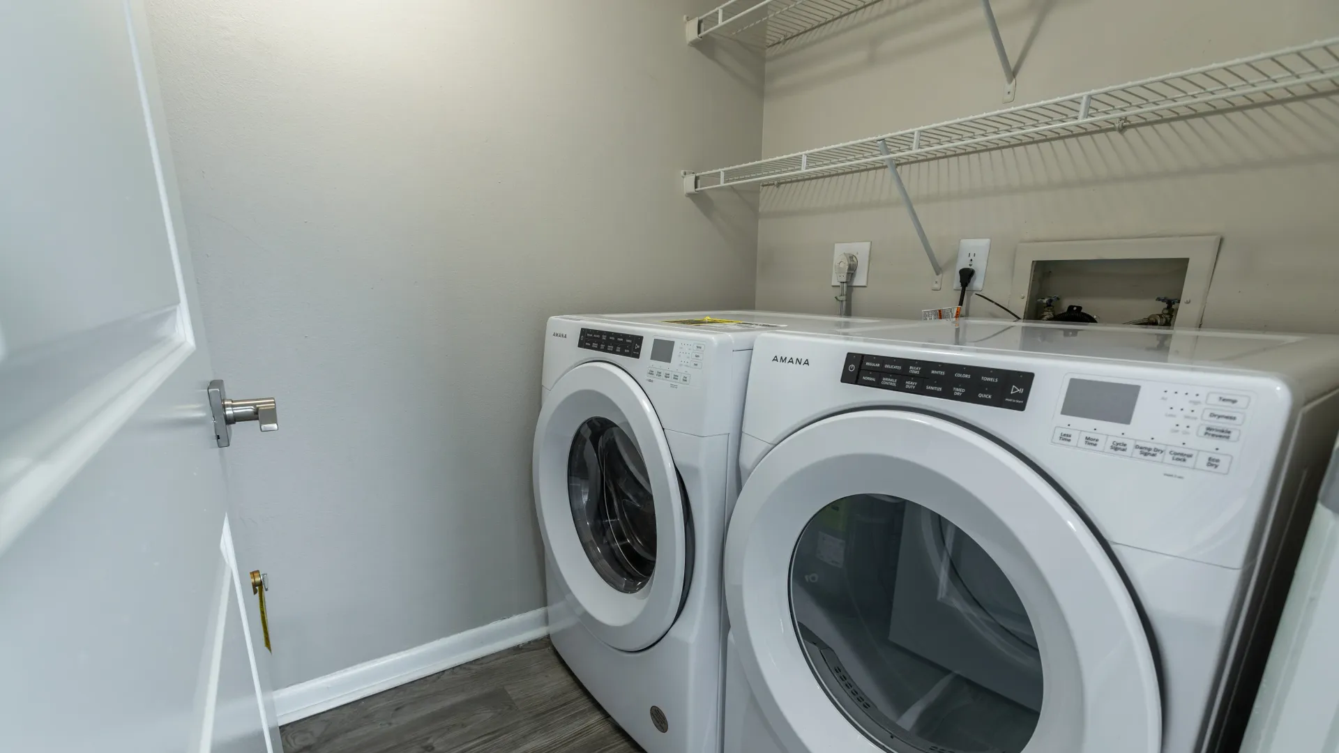 A dedicated laundry haven showcasing front-loading washer and dryer units with additional overhead shelving.  