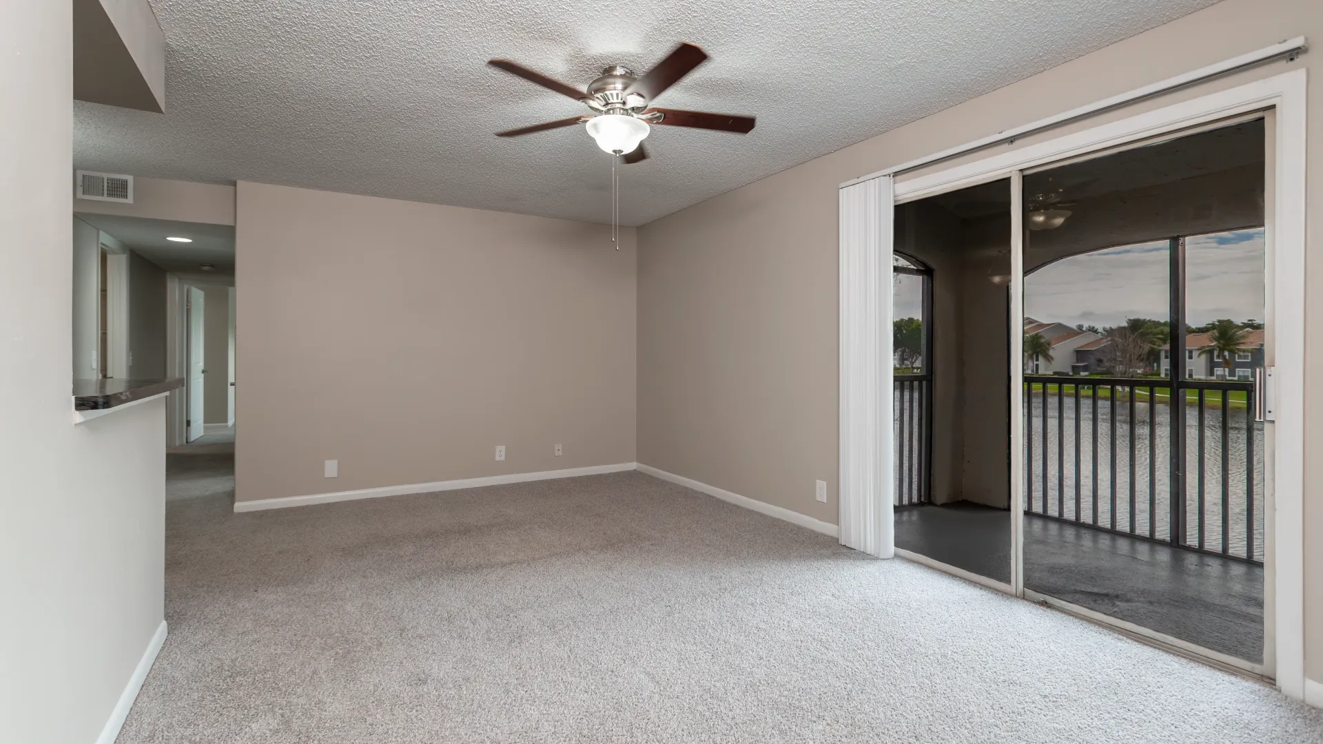 The plush carpeted living room showcases breathtaking lake vistas through sliding glass doors, seamlessly leading to an expansive screened patio.