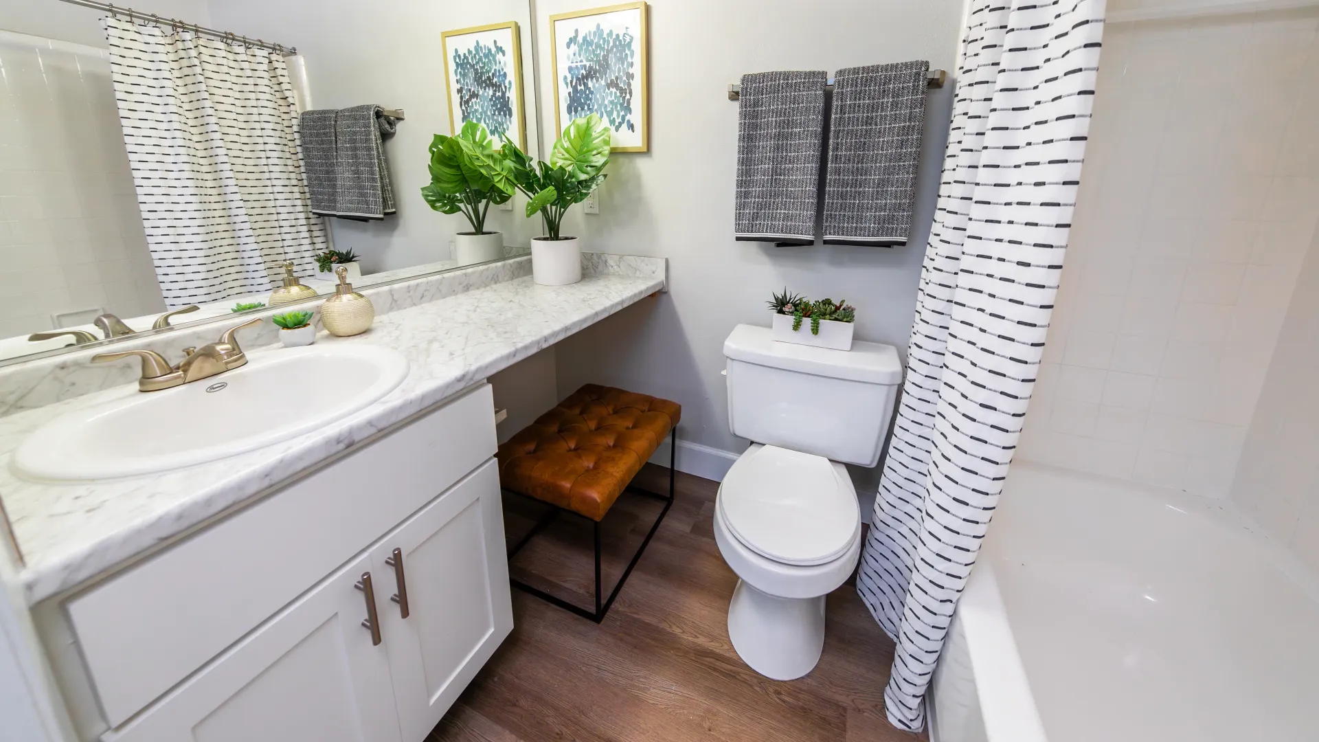 Immerse yourself in a bright bathroom with wood-style flooring, sprawling granite-style countertops, and a massive mirror.