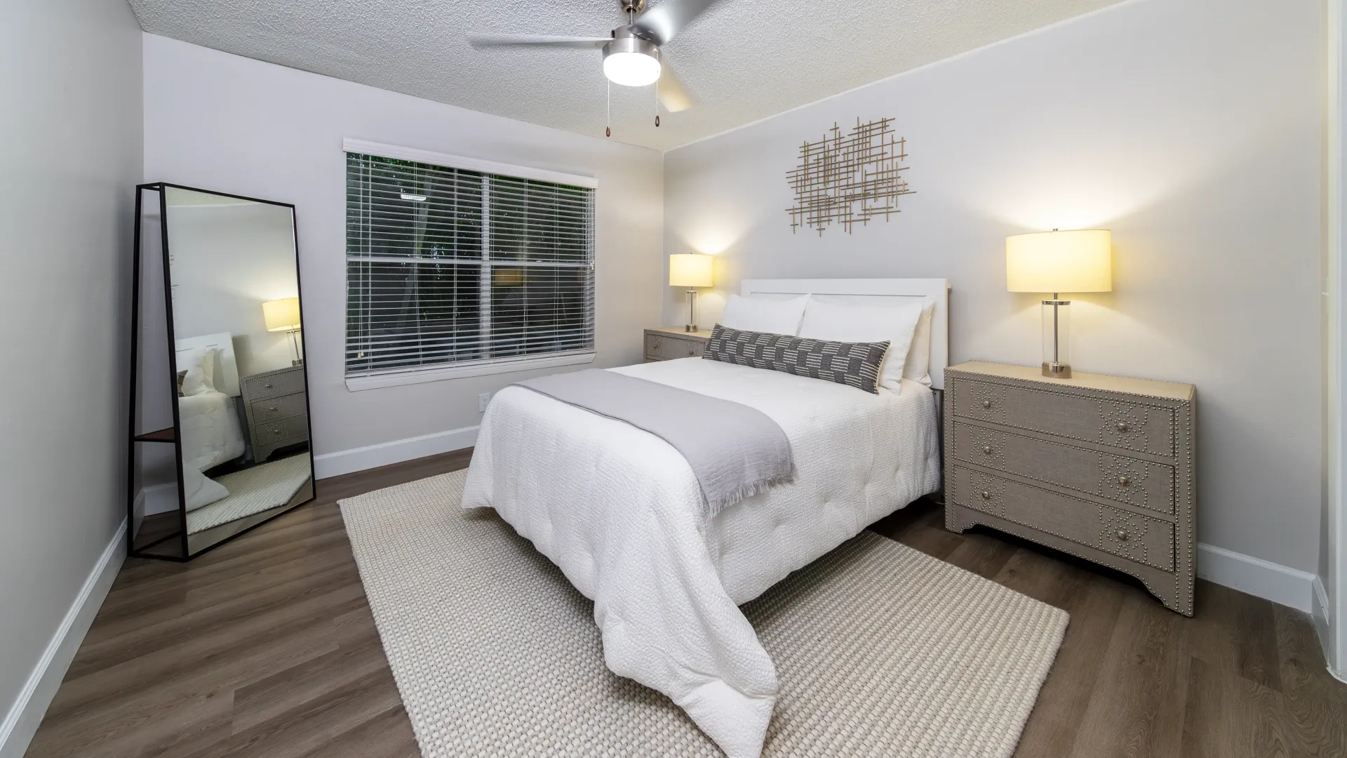 An expansive master bedroom outfitted with queen size bed and slick plank-like flooring. 