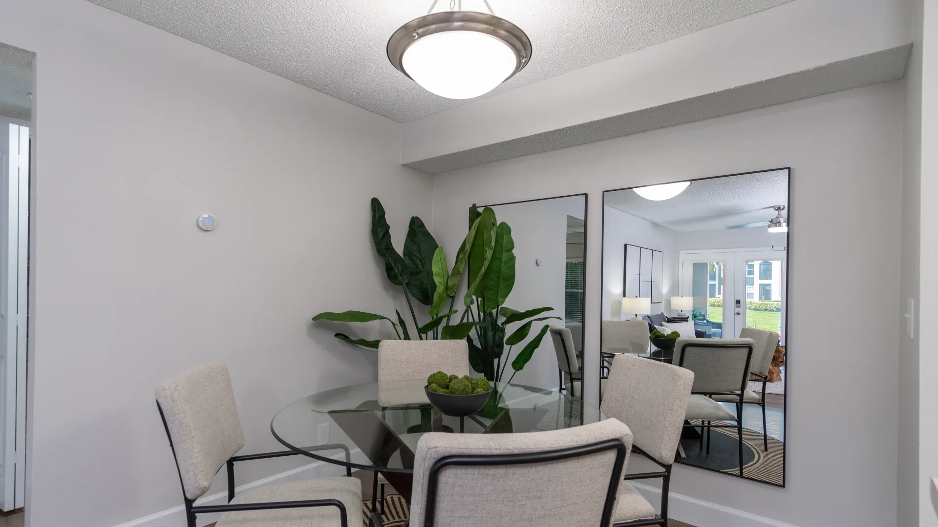 An elegant lighting fixture hangs above a dining table with four elegant chairs. 
