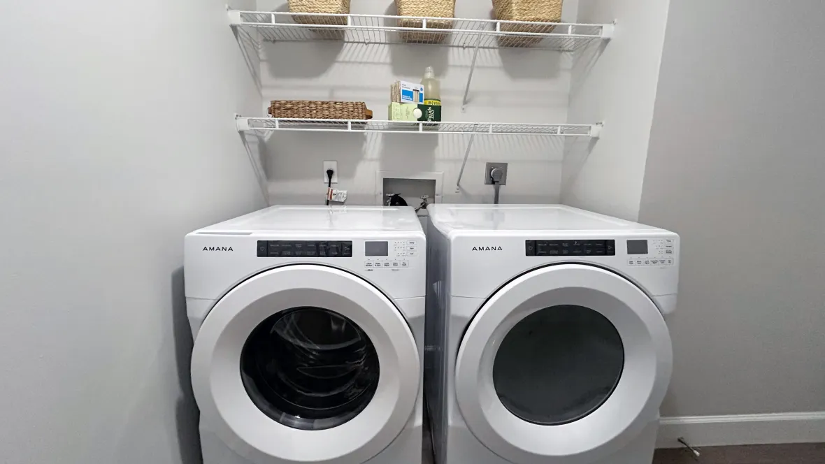 A washer and dryer with wire shelving above. 
