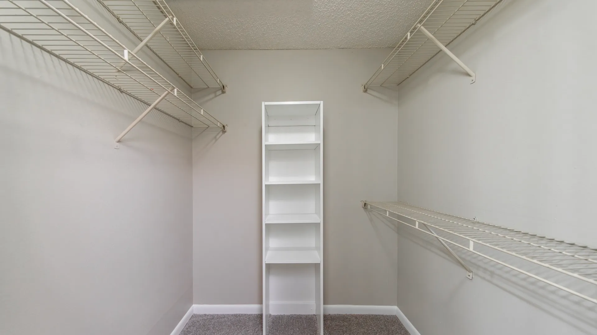 An enormous walk-in closet with customized open wire shelving and a bonus built-in bookcase, providing versatile storage for your wardrobe and accessories.