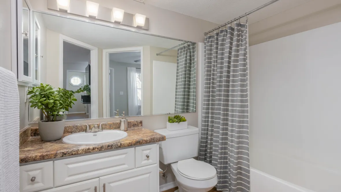 Your spacious and airy bathroom sanctuary, featuring granite-style countertops, wood-style flooring, and a large mirror, is the perfect place to unwind and pamper yourself.