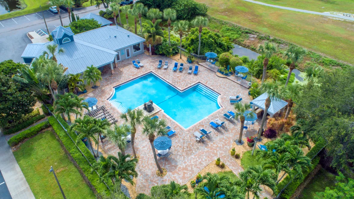 Aerial view of the lush pool deck oasis complete with a pergola, cabana, hammocks, and endless seating options, inviting you to relax and revel in the ultimate resort lifestyle.