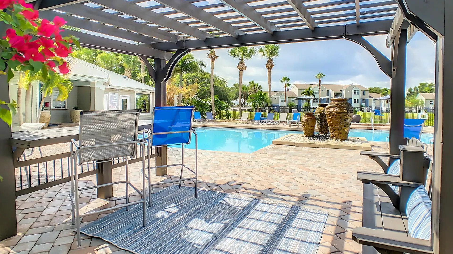 Poolside pergola with seating at Beachway Links Apartments overlooking the resort-style swimming pool and outdoor lounge area.