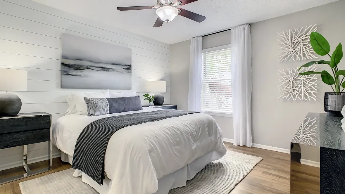 A generously sized, luxurious master bedroom retreat boasting a large window, convenient ceiling fan with lights, and refined wood-like floor offering a peaceful haven for restful nights.