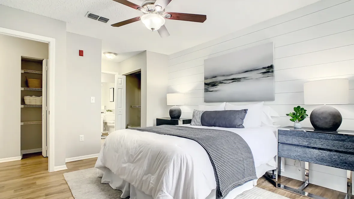 A deluxe master bedroom showcasing its abundant spaciousness, glossy wood-style floors, attached private bath, walk-through closet, and a touch of serene luxury.