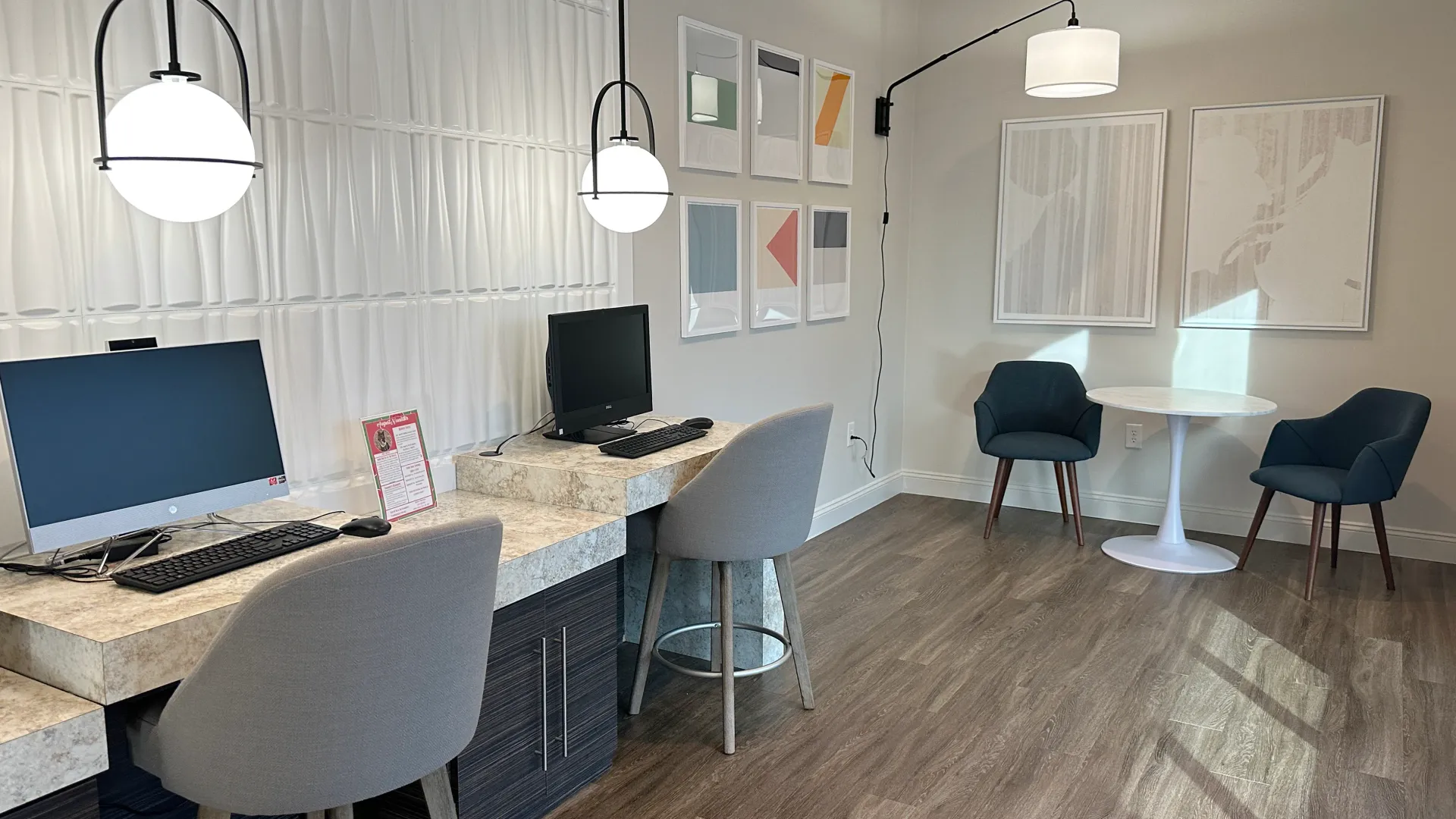 A fully equipped resident business center offering multiple workstations, a complimentary printer, and a cozy, secluded seating area for focused work.