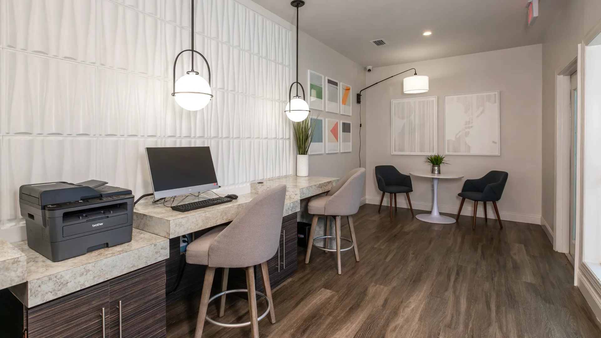 Modern resident business center with computer station, printer, and comfortable seating at Grand Oaks Apartments.