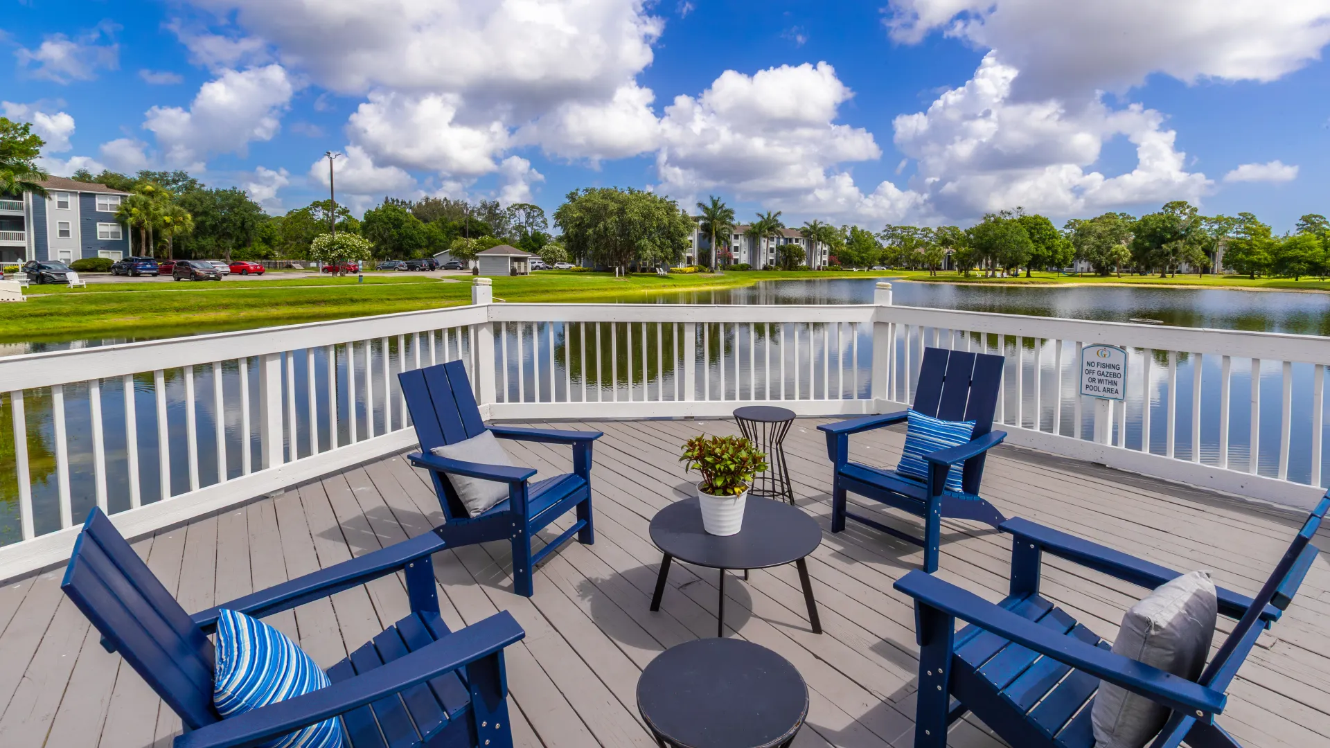 Lakefront deck with blue Adirondack chairs and small tables overlooking the lake.