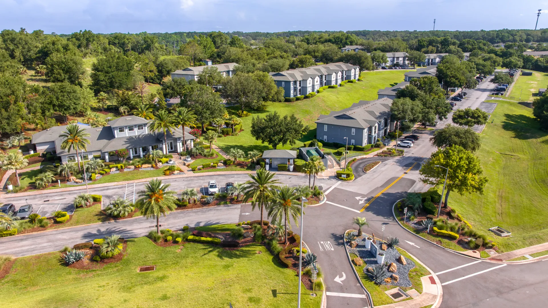 Bird’s-eye view of Elevate 155’s gated entrance, clubhouse, and apartment buildings nestled in greenery.