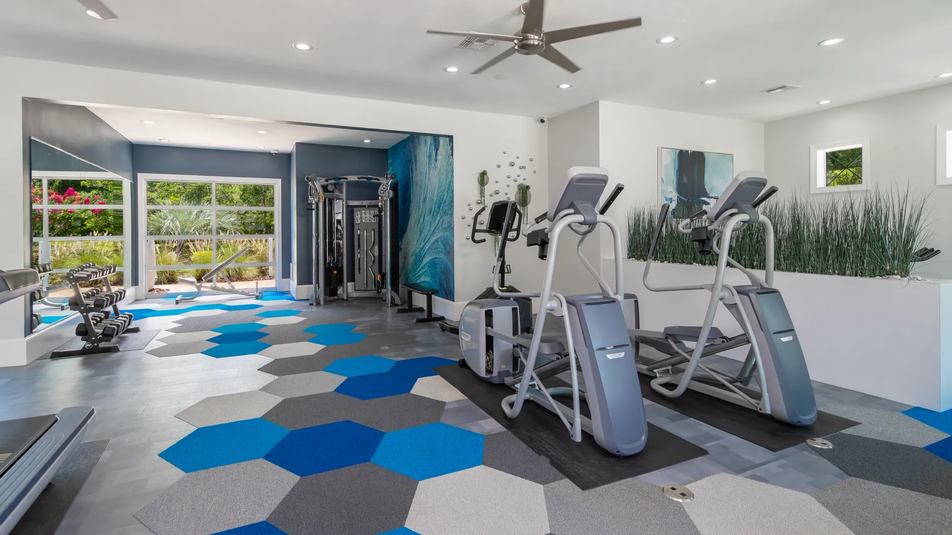 Fitness center at Elevate 155 featuring ellipticals, strength machines, and bright windows.