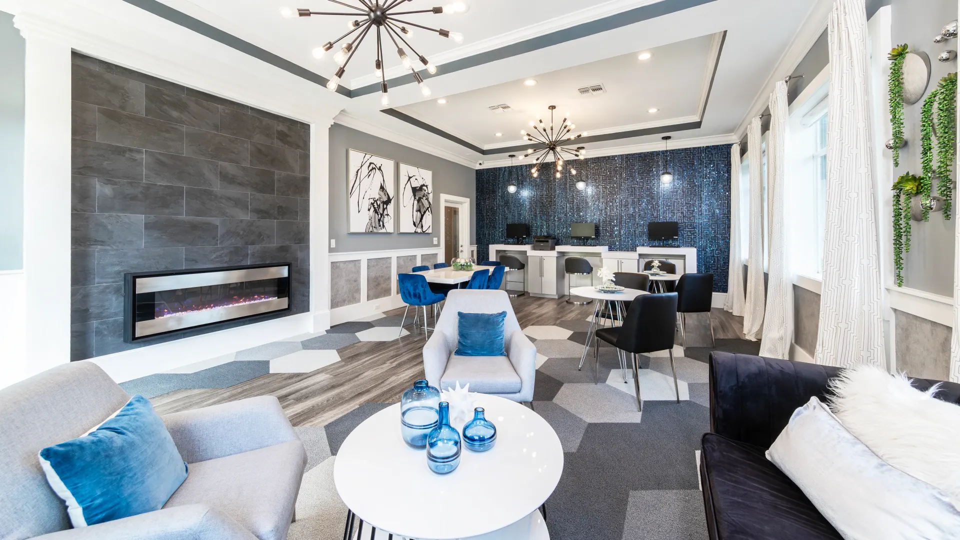 Modern business lounge at Elevate 155 with fireplace, blue accent chairs, and contemporary lighting.